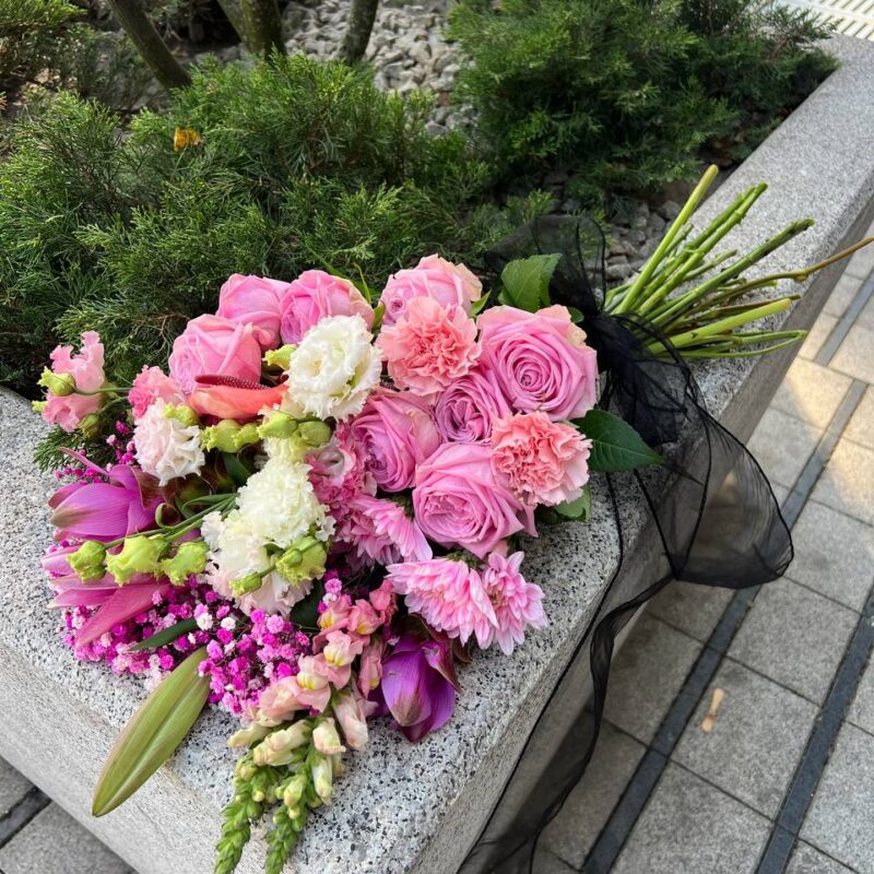 Wiązanka pogrzebowa w odcieniach różu z eleganckimi dodatkami kwiatowymi.